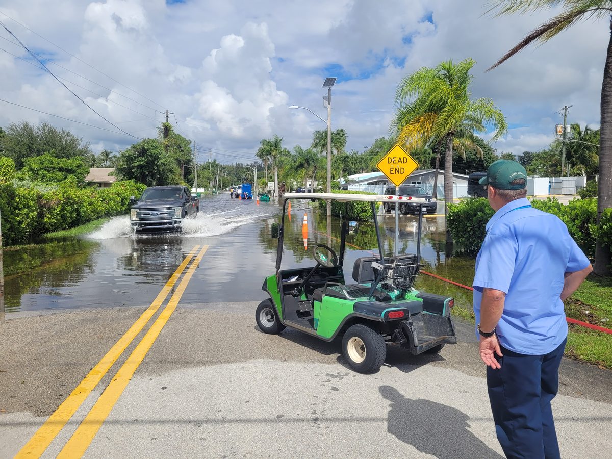Golf cart parked at the edge of a flooded Dania Beach street during the Fort Lauderdale king tide