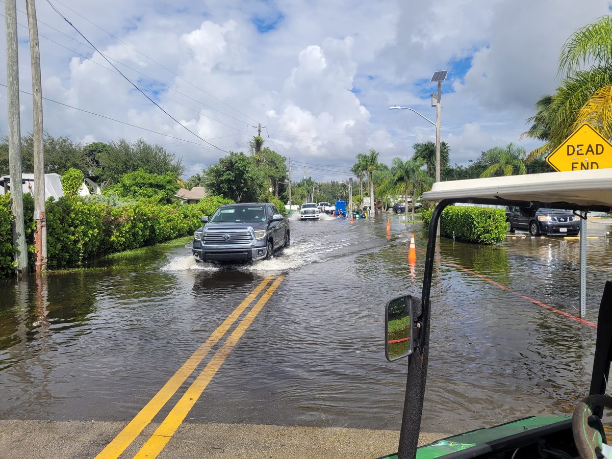 Pickup truck driving through king tide flooding on a Dania Beach residential street near Fort Lauderdale