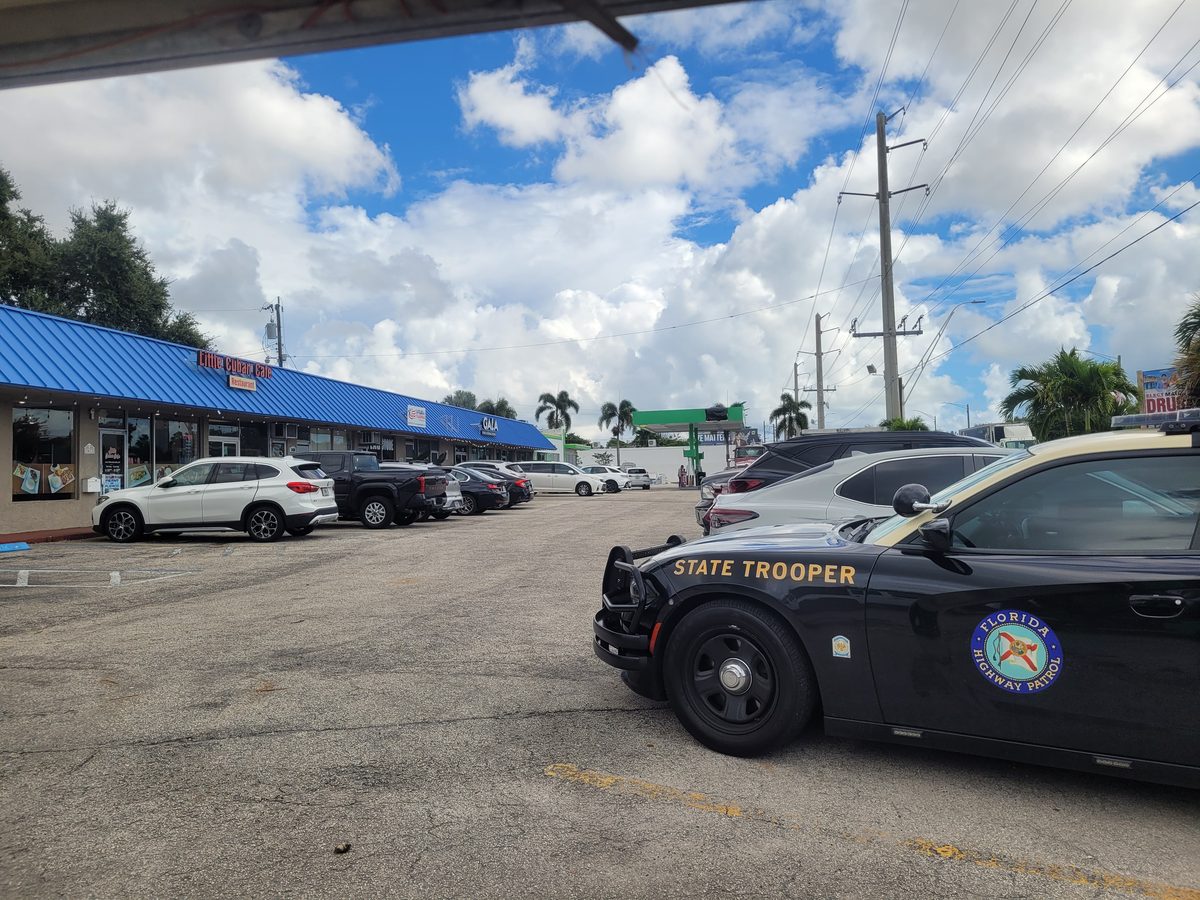 Florida Highway Patrol cruiser parked at a Dania Beach shopping plaza during king tide flooding